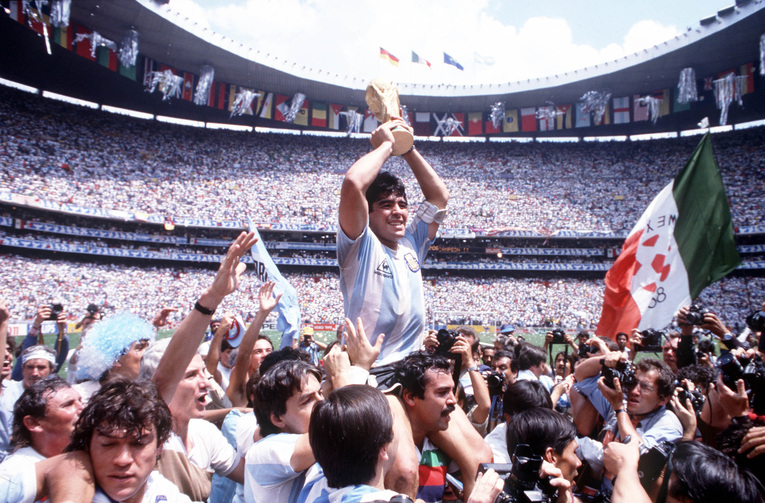 Diego Maradona brandit fièrement le trophée de la Coupe du monde au milieu des supporters et des photographes